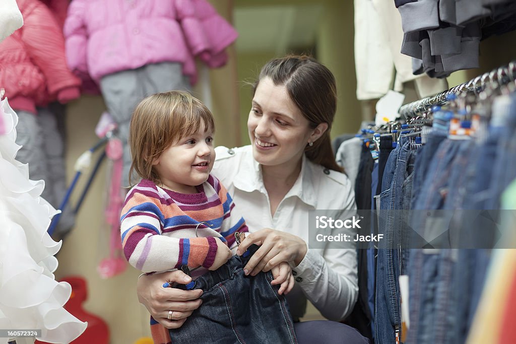 Happy woman and child chooses jeans Happy woman and child chooses jeans at shop Baby Clothing Stock Photo