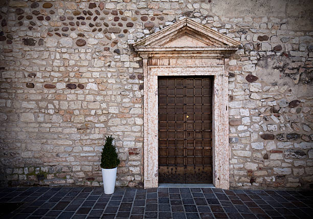 Heavy mediaval entrance door on stone wall. Border vignetting