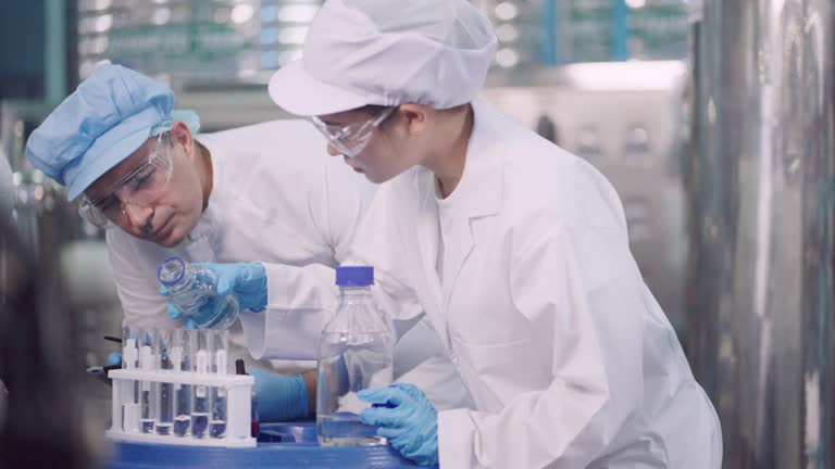 Professional food scientist worker or nutritionist or quality control officer, wearing hairnet and sterile clothing, checking quality of  water production  .