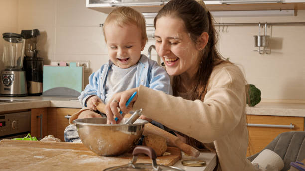 istock Happy smiling mother playing and having fun with her little baby son while making dough and baking pastry on kitchen. Concept of little chef, children cooking food, healthy nutrition. 1605745097