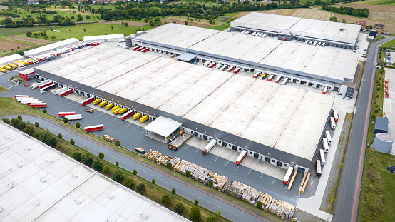 Loading bay, truck parking lot, unrecognisable industrial building, logistics - aerial view - tracking shot