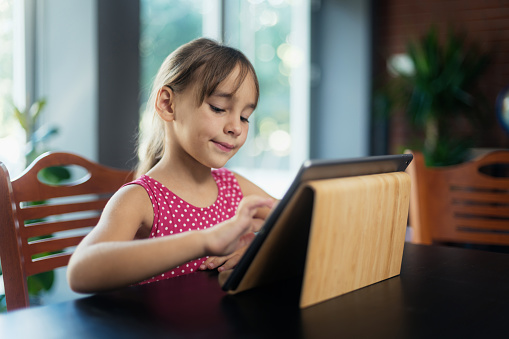 Little child girl using digital tablet at home