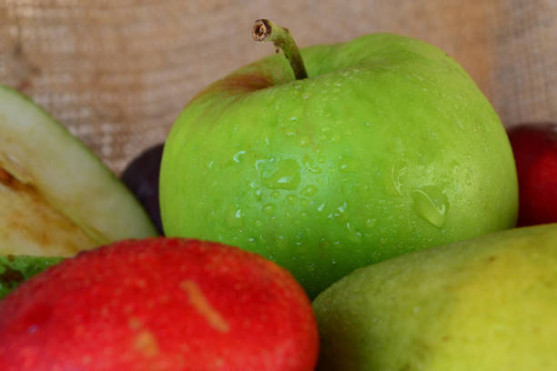 Organic unwashed apples on a cutting board on a white kitchen counter.