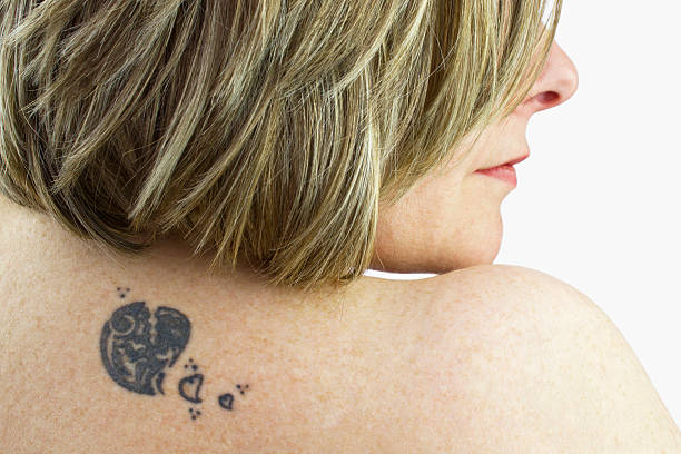 Tattoo of a woman Tattoo on the back of a young woman on a white background. back shoulder tattoos for women pictures stock pictures, royalty-free photos & images
