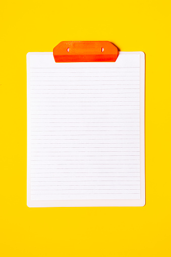 High angle view of clipboard over yellow background with white paper in blank