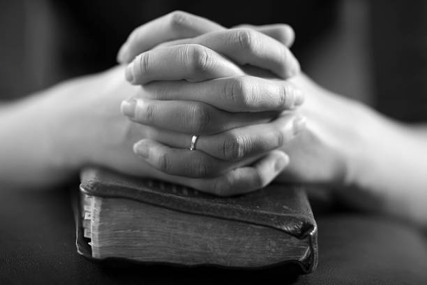 istock Folded hands sitting on top of a book 160581622