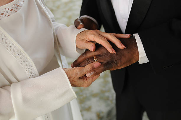 istock elderly mixed couple exchanging wedding rings 160582152