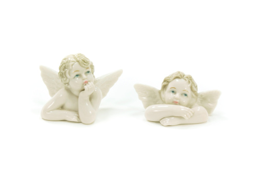 Two ceramic statuettes of angels with wings on white background