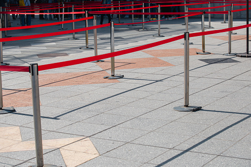 Temporary fencing to organize the direction of the flow of people - metal posts and red tape - queuing for the public