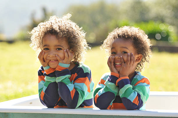 Two young brothers dressed alike taking photo outside in tub stock photo