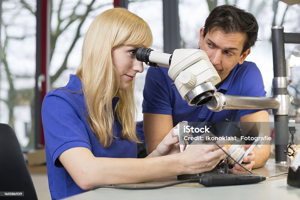 Dental technicians working on mold under a microscope Dental technicians working on mold under a microscope in a lab Adult Stock Photo