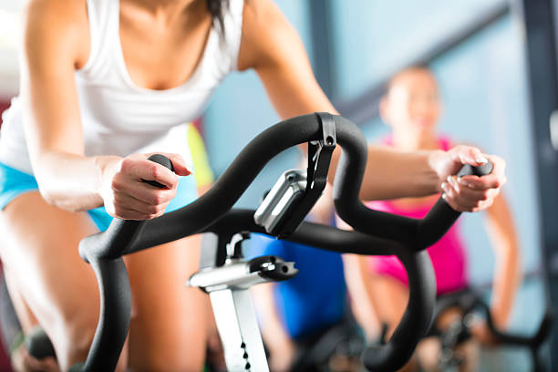 jeunes vélo d'exercice dans la salle de sport - spinning instructor exercising gym photos et images de collection