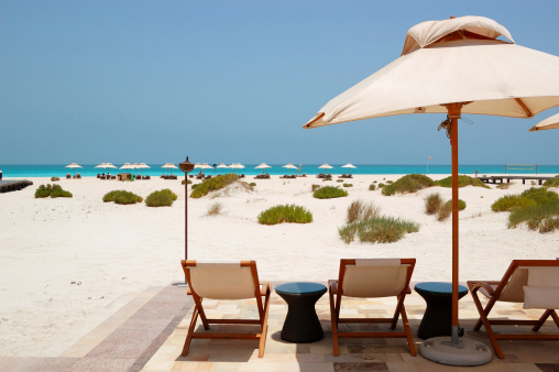 Sunbeds and umbrellas at the beach of luxury hotel, Abu Dhabi, UAE