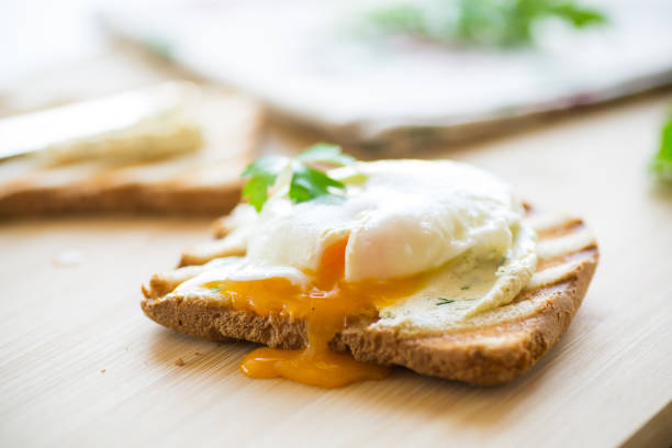istock Fried toast bread with spread and poached egg, on a wooden table. 1605911843