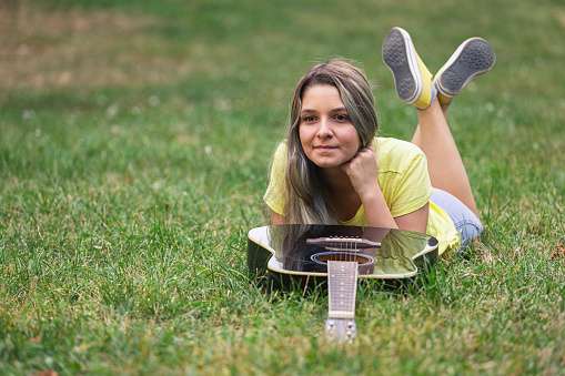 Beautiful young girl laying on grass with a guitar