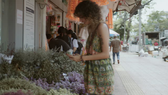 A female tourist enjoy walking at the flower shop  and take a picture with flower at Flower Market in Bangkok