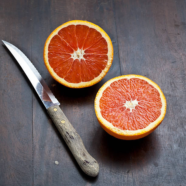 Naranja valenciana cortado por la mitad en la mesa de madera oscura - foto de stock