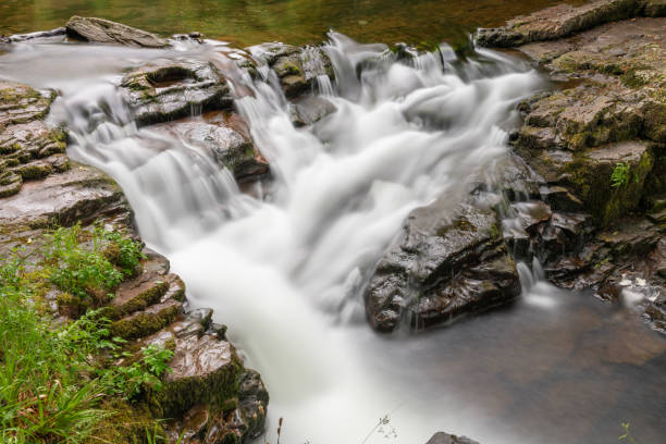Long exposure of a waterfall on the East Lyn river flowing through the woods at Watersmeet in Exmoor National Park