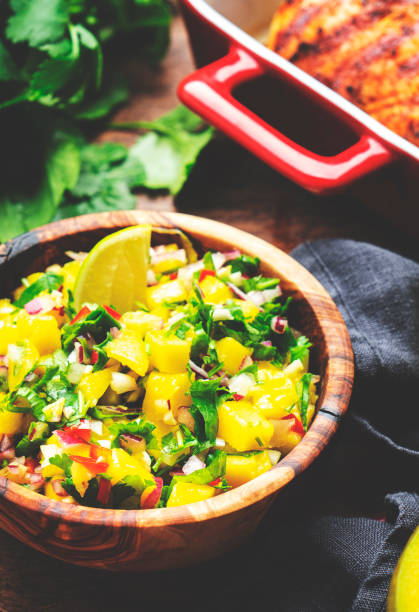 istock Mango salsa sauce with chili peppers, red onion, garlic, lime and cilantro, rustic wooden table background, top view 1606024328