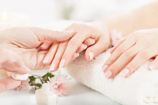 Close up of beautiful female hands being manicured in a nail salon