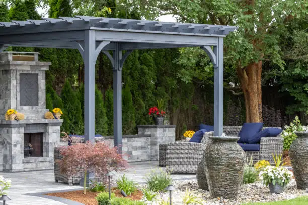 Landscape architecture featuring pergola and stone fireplace with stone urn water fountains for backyard patio oasis