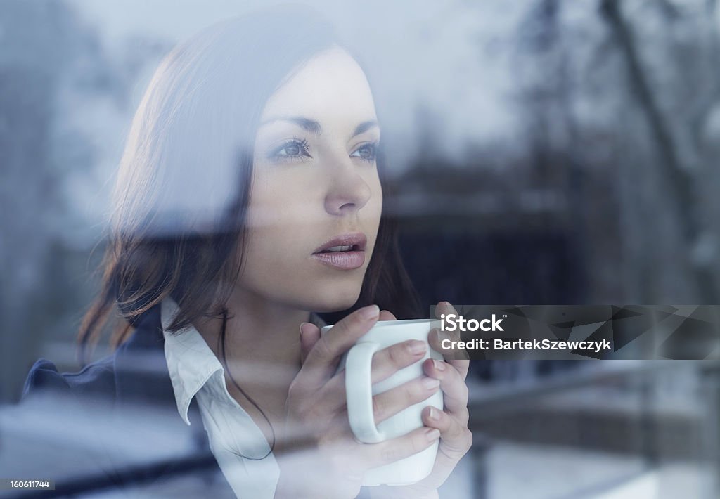 Young woman looking through the window Young woman drinking coffee looking through the window Adult Stock Photo