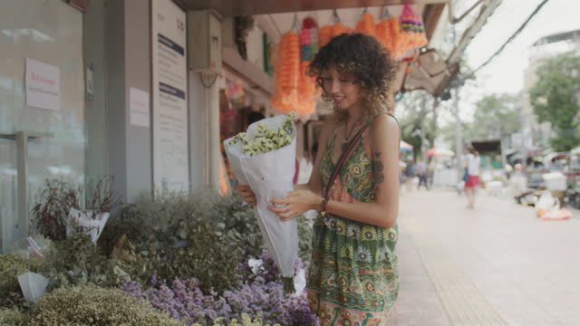 Female tourist customer choosing flowers  at the flower market while exploring Bangkok on holiday.