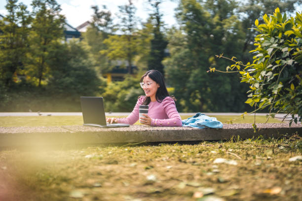 istock Asian Female Chatting Online While Using Laptop on Concrete Bench 1606135846
