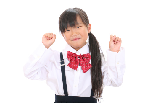 Little asian school girl raising her arm in sign of victory