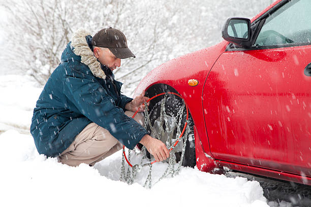 istock Mid aged male driver mounting car tyre chains 160617571