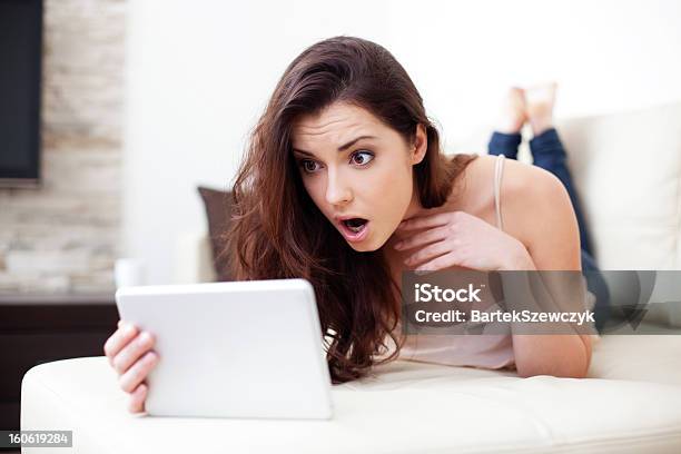 Surprised Woman With Tablet On Couch Stock Photo - Download Image Now - Adult, Adults Only, Anger