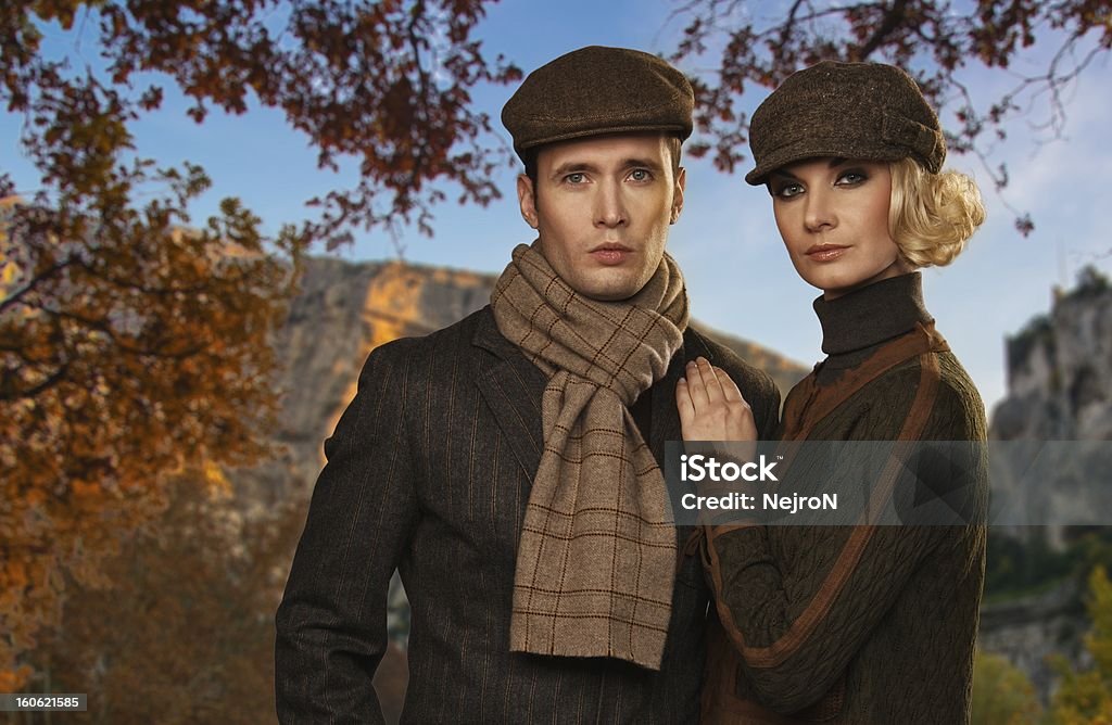 Elegant couple in caps against autumnal landscape Adult Stock Photo