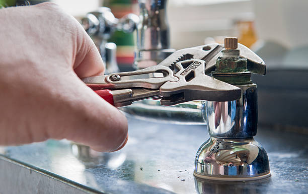 Plumber Real life situation - A plumber uses adjustable grips to remove a worn insert from a set of kitchen taps with a view to replace the damaged part. wrench photos stock pictures, royalty-free photos & images