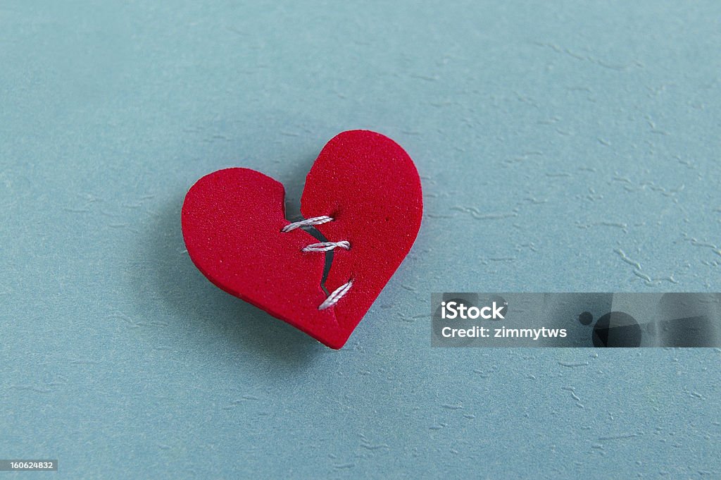 mended heart small red heart, broken with threaded stitches Heart Shape Stock Photo