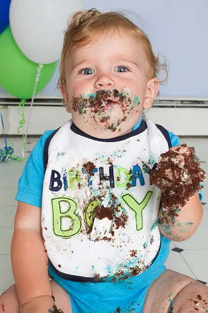 baby boy on first birthday after he indulges in cake
