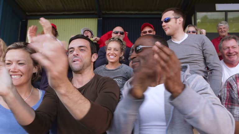 Enthusiatic crowd of sports fan spectators. This could be a scene from the stadium crowd at the olympics, tennis tournament, American football, soccer match or baseball. People young and old cheering and smiling.