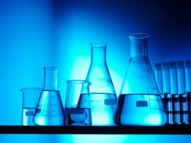 Conical flasks, science beakers and test tubes for research with blue coloured lighting. 