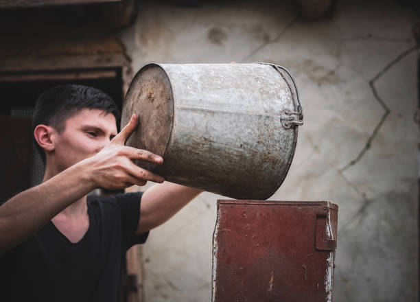 istock A young guy pours wheat from a bucket into a crusher. 1606365674