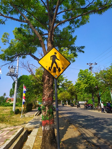 traffic signposts with many pedestrians crossing the road