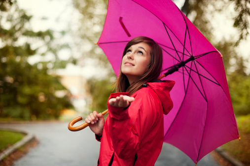Beautiful woman with umbrella checking for rain