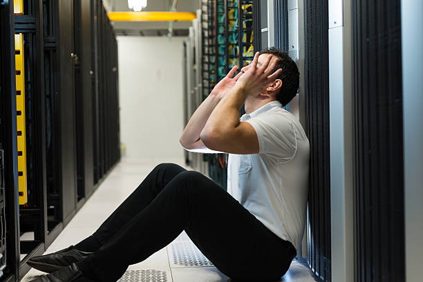 Server failure Business man sitting in a data center looking frustrated with the current system. He is looking for a better IT solution. computer plan fiber optic engineer stock pictures, royalty-free photos & images