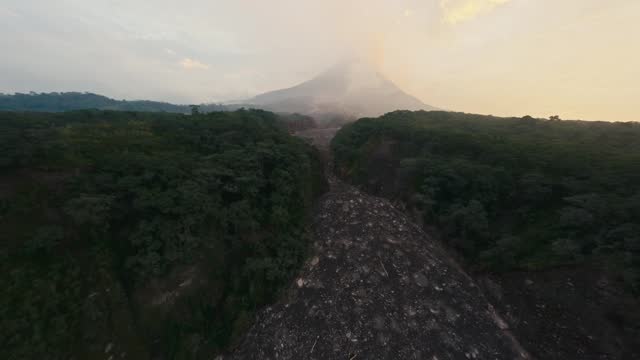 Aerial view tropical forest canyon with frozen volcanic lava and smoke eruption active volcano sky