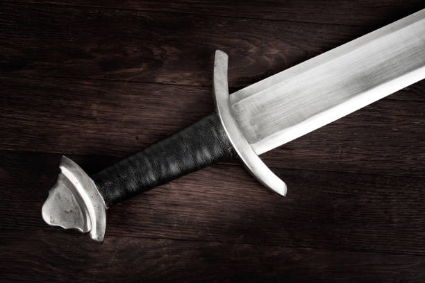 istock Medieval sword on wooden backgrond. 1606550190