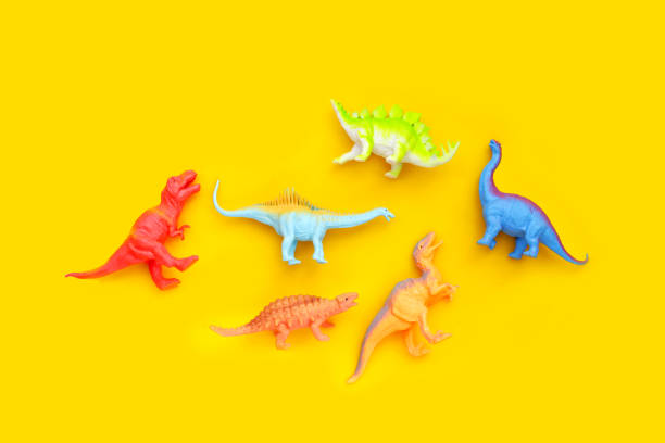 istock Plastic dinosaur toys on yellow background. Top view 1606564270