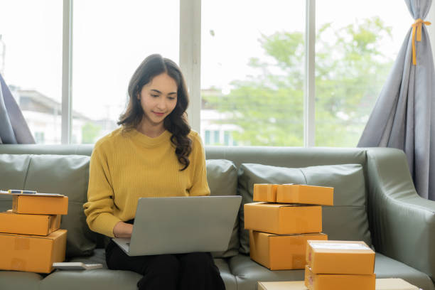 istock A young Asian small business entrepreneur starts using a smartphone and laptop computer to check orders from the web, owns a work at home online seller prepares product parcel packs for delivery. 1606594367