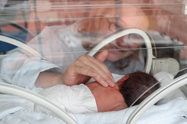 Female doctor examining newborn baby in incubator. Night shift