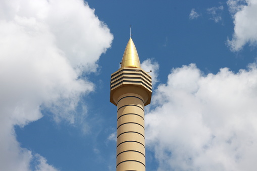 mosque minaret isolated on blue sky and white clouds
