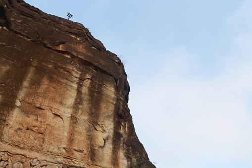 AERIAL: Scenic limestone wall and female climber advancing on demanding route. Young woman climbing on a sharp end of rope. Magnificent climbing area with picturesque views at sunny Karst Edge.
