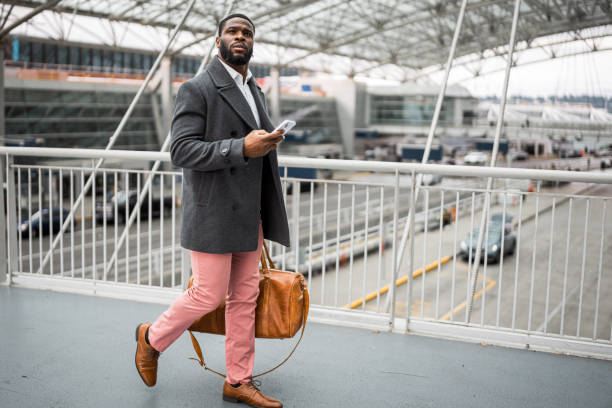 istock Man smiles, walking on a bridge with his phone and luggage 1606720253