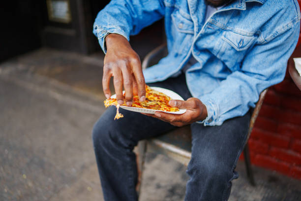 istock Man holds slice of piece while sitting outside restaurant 1606720812